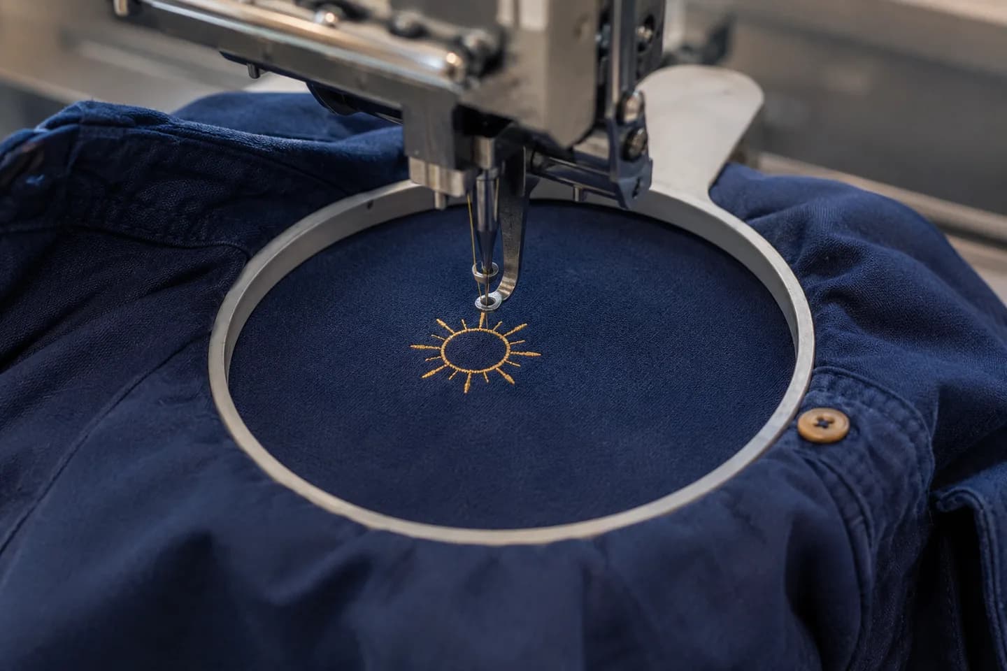 Illustrative image of a sun motif being embroidered on navy fabric